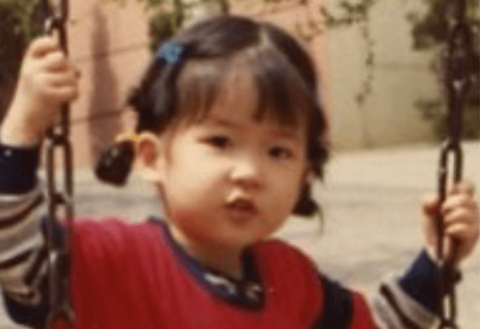 韓国女優イ・ボヨンの幼少期の画像。ブランコに乗っていて髪型は二つに結んでいる。