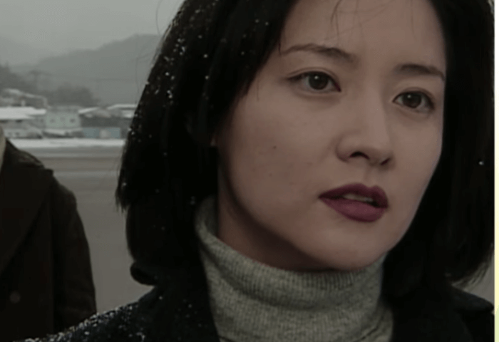 韓国女優イ・ヨンエが1999年に出演した「ウンビリョン」のワンシーン。
雪の降る寒い時に海辺で深刻な話をしている様子。
グレーのモックネック（タートルネック）のニットを着用。
前髪無しのボブヘアで、濃い目の口紅をしている。